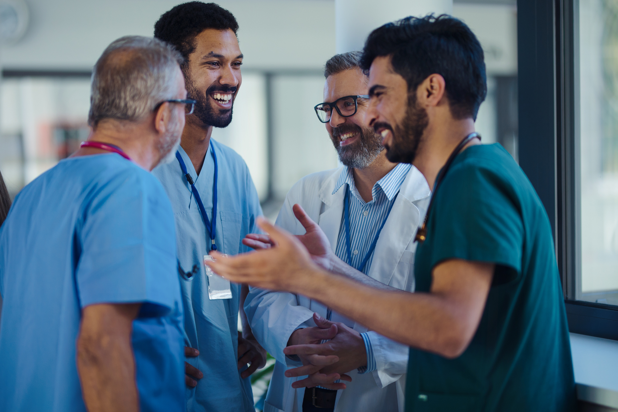 Happy doctors talking and smiling at hospital corridor.